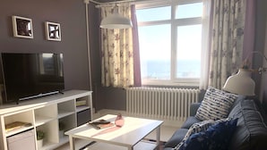 A living room with a television, white shelves, a coffee table, a sofa, and a window with curtains. - Mehmet Bey Suites (Istanbul)