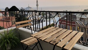 A balcony with a wooden table and chairs, overlooking a cityscape with a mosque and a minaret. - Mehmet Bey Suites (Istanbul)