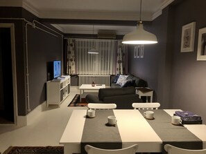 A modern living room with a dining area, a sofa, a TV, and a radiator. - Mehmet Bey Suites (Istanbul)
