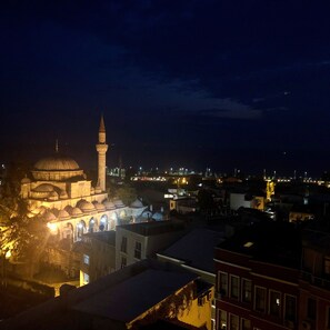 A night view of a historic building with a prominent dome and a tall minaret, surrounded by residential buildings. - Mehmet Bey Suites (Istanbul)
