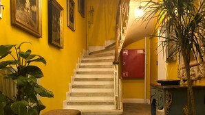 A staircase with a red fire alarm box, a patterned rug, and a potted plant. - Mehmet Bey Suites (Istanbul)