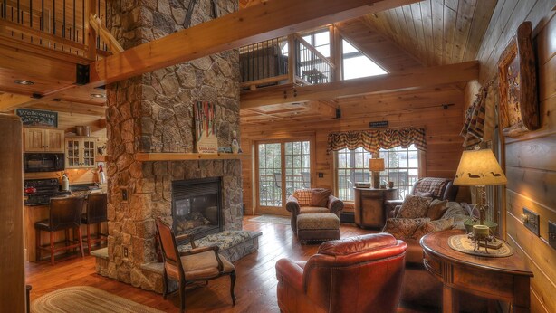 A log cabin interior with a stone fireplace, wooden furniture, and a cozy seating area. - 🐾28 Bunker Ave - Shared waterfront and access to Rangeley Lake, dog friendly (Rangeley)