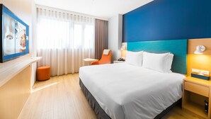 Une chambre d’hôtel avec un grand lit, un bureau, une chaise, une télévision et une fenêtre avec des rideaux.