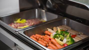 A buffet with various food items including sausages, vegetables, and meat.