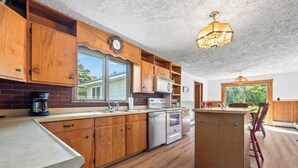 A kitchen with wooden cabinets, a built-in oven, and a coffee maker. - 🐾Dallas Ridge - Dog friendly four seasons home in Rangeley! (Rangeley)