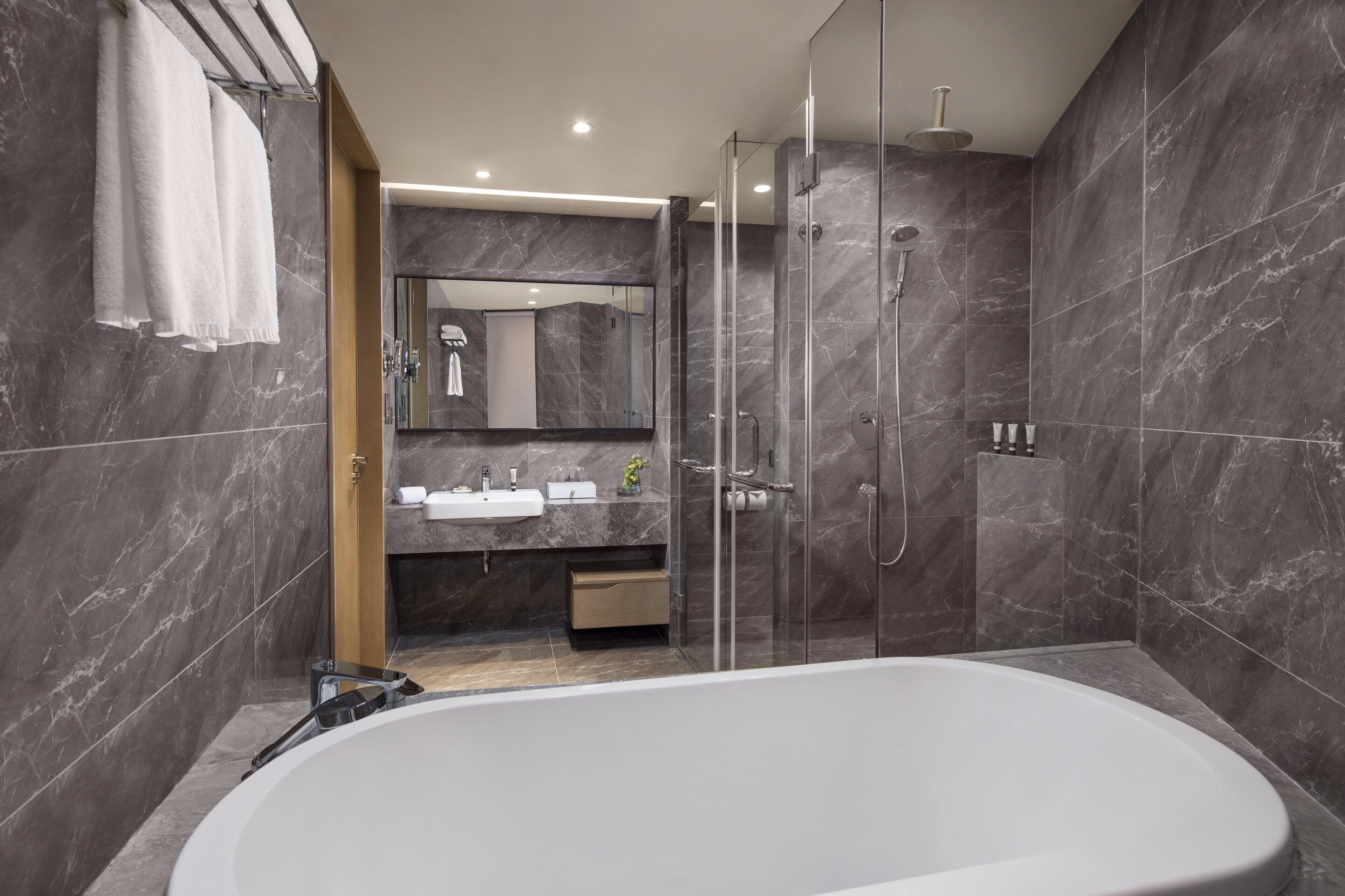 Un baño moderno con una bañera grande, una ducha con mampara de vidrio y un tocador con espejo.