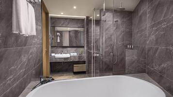 A modern bathroom with a large bathtub, a glass-enclosed shower, and a vanity with a mirror.