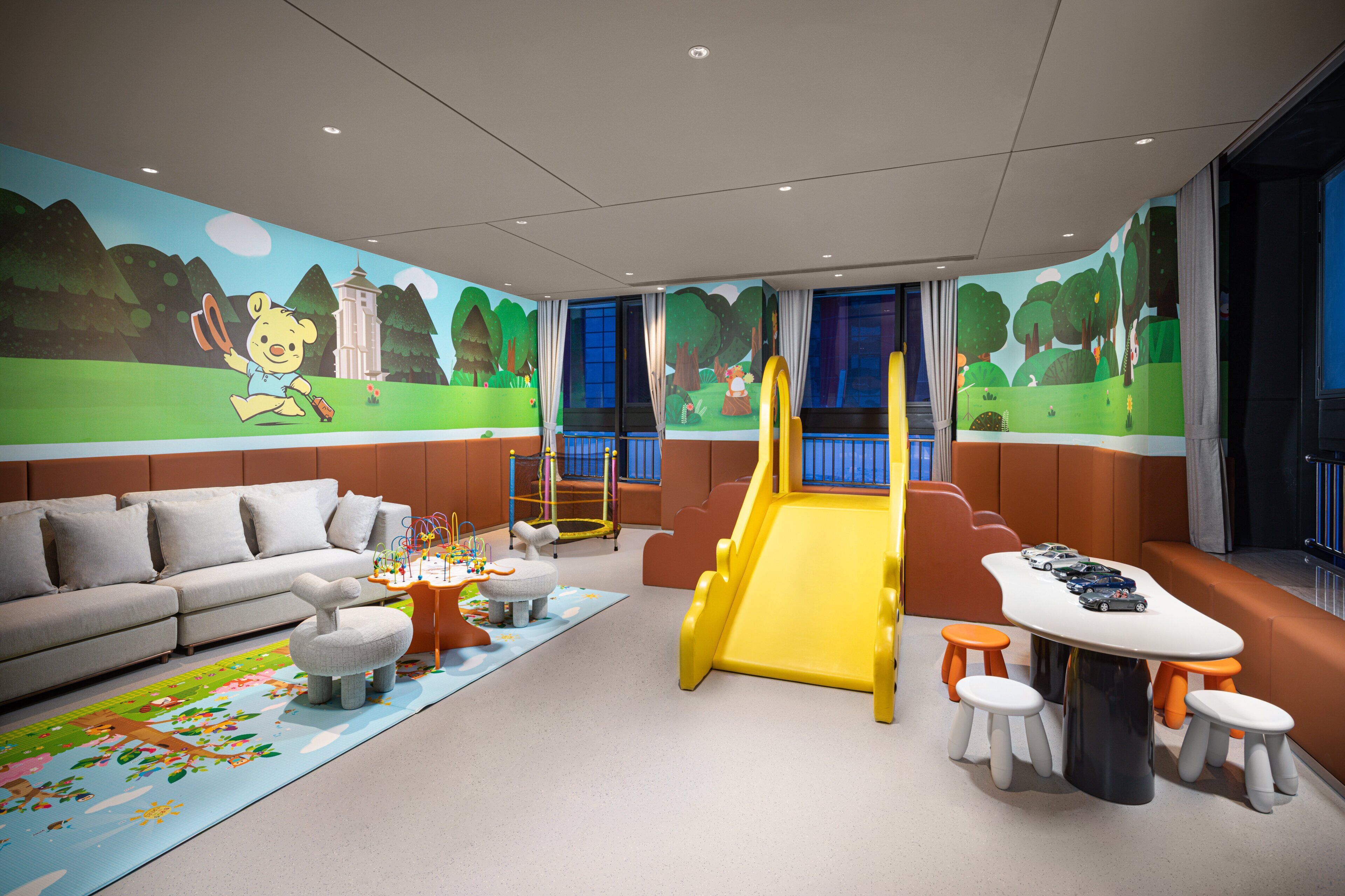 A children's play area with a slide, seating, and a mural.