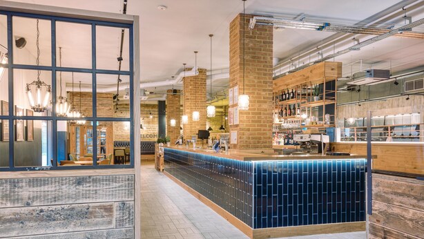 A modern bar area with a blue-tiled counter, wooden accents, and hanging lights. - Premier Inn London Sutton (Sutton)