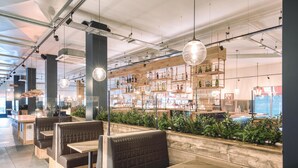 A restaurant with booth seating, wooden tables, hanging pendant lights, and shelves stocked with bottles. - Premier Inn London Sutton (Sutton)