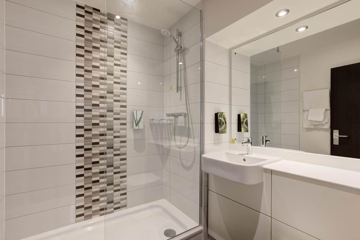 A modern bathroom with a shower, a sink, and a large mirror.