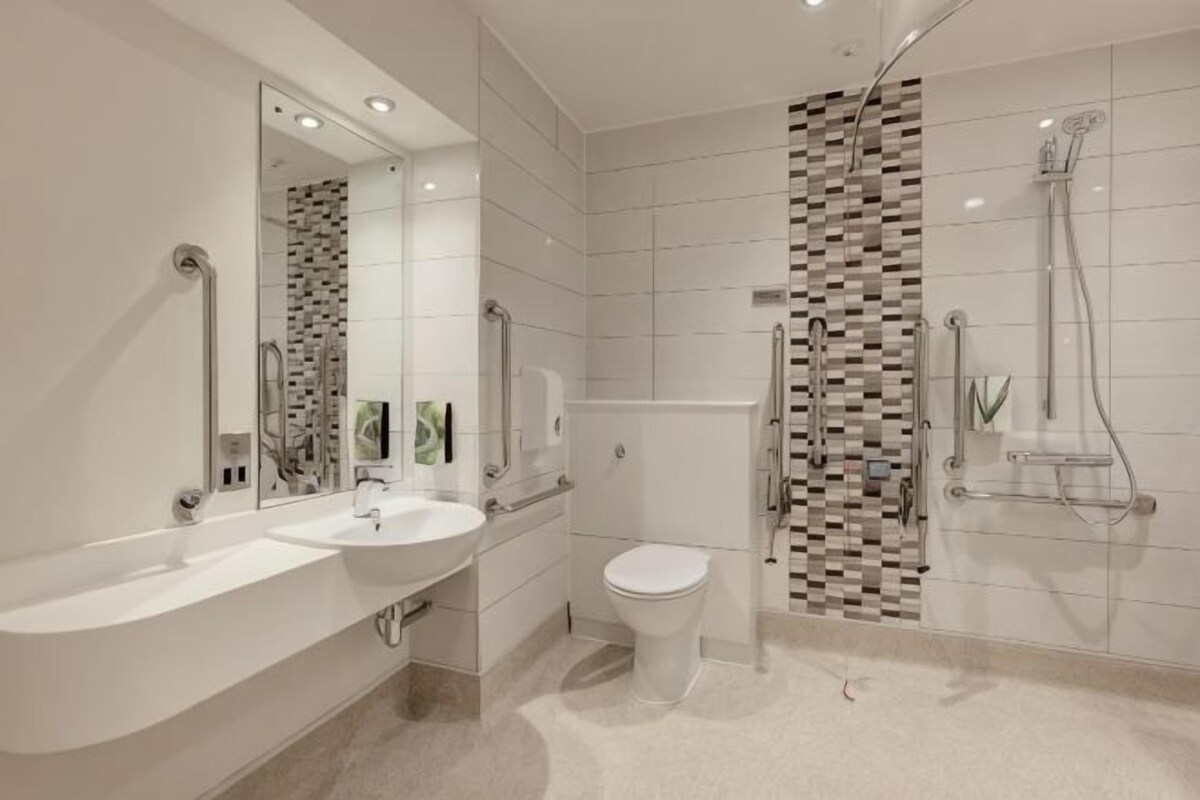 A modern bathroom with a large bathtub, a separate toilet, and a shower area.