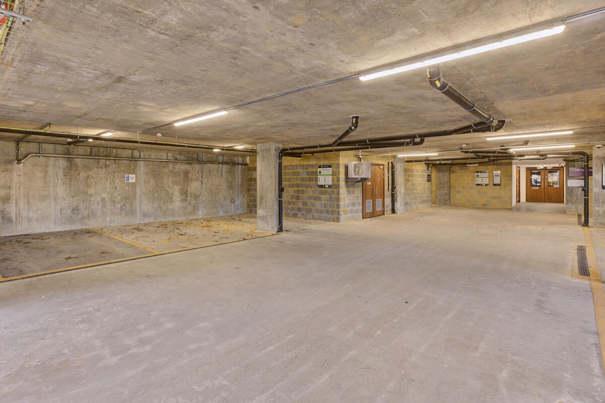 An empty parking garage with concrete walls, a ramp, and multiple doors.