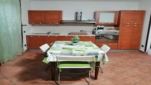 A compact kitchen with wooden cabinets, a tiled floor, and a dining table with chairs. - "The Corte Giovanna" (Rescaldina)