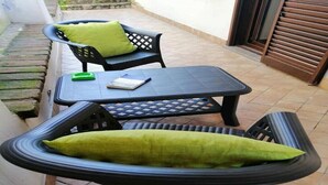 A small outdoor seating area with two black plastic chairs and a table, each with a green cushion. - "The Corte Giovanna" (Rescaldina)