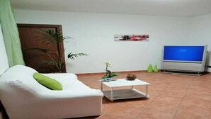 A living room with a white sofa, a small coffee table, a TV, and a potted plant. - "The Corte Giovanna" (Rescaldina)