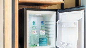 Un refrigerador con dos botellas de agua Gerolsteiner Nature y un cartel que indica agua de cortesía.