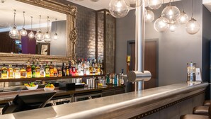 Zona de bar con un espejo, lámparas esféricas colgantes y una variedad de botellas de licor.