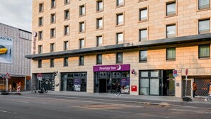 Un hotel de varios pisos con un llamativo letrero de Premier Inn, una cafetería y un parador de taxis.