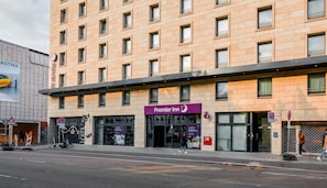 Et hotel med flere etager, med et tydeligt Premier Inn skilt, en café og en taxaholdeplads.