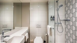 Un baño moderno con ducha acristalada, lavabo blanco y retrete.
