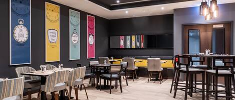 A modern restaurant interior with high tables, striped chairs, and a variety of wall art.