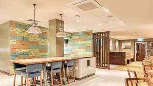 A modern hotel lobby with a wooden wall, a bar area, and seating arrangements. - Premier Inn Penzance (Penzance)
