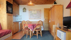 A compact kitchen with wooden cabinets, a dining table with chairs, a microwave, and a television. - 10m from ski slopes, 1st floor, balcony, 33m², Méribel-Mottaret (Méribel - Les Allues)