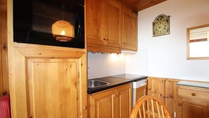 Una cocina de madera con un fregadero, estufa y un reloj en la pared.