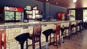 A bar area with a stone counter, wooden chairs, and a fan. - Pakali Lodges (Livingstone)