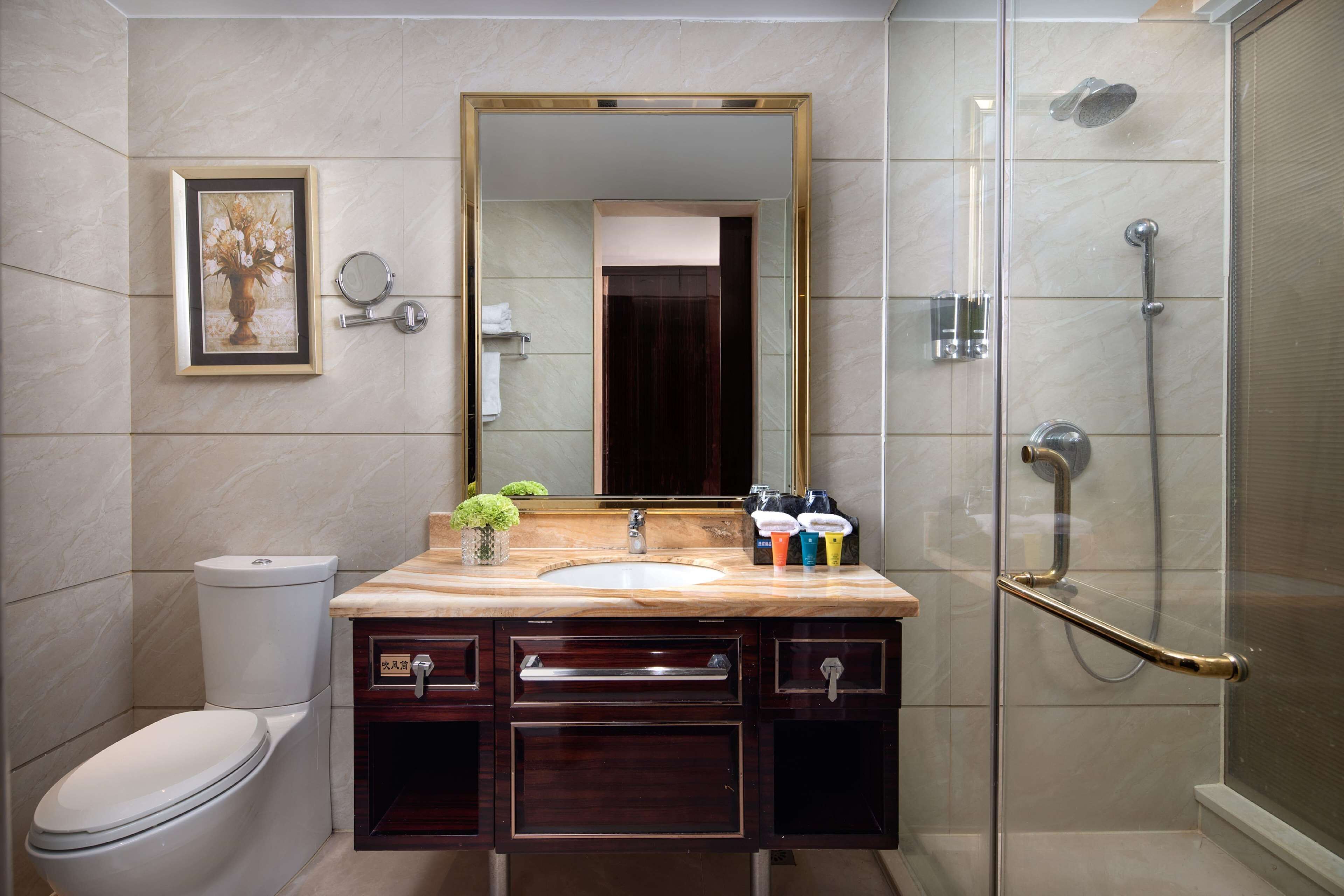 A bathroom with a toilet, sink, mirror, and shower.