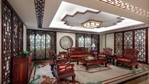 A traditional room with wooden furniture, a patterned ceiling, and decorative screens.