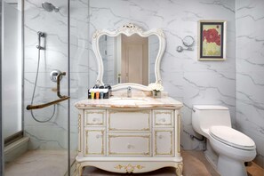 A bathroom with a marble vanity, a white toilet, and a shower enclosure.