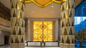 A lobby with marble columns, a reception desk, and a large illuminated wall.