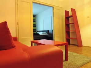 Cozy living space with a sofa, wooden table, and shelving unit.