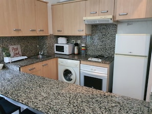 A kitchen with granite countertops, a microwave, a toaster, a washing machine, and a refrigerator. - 19 Comfortable Apartment in City (Tarragona)
