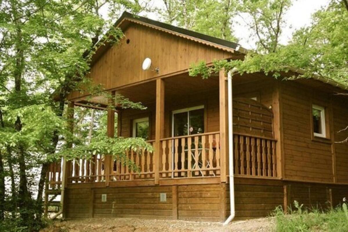 A wooden cabin with a balcony, surrounded by trees.