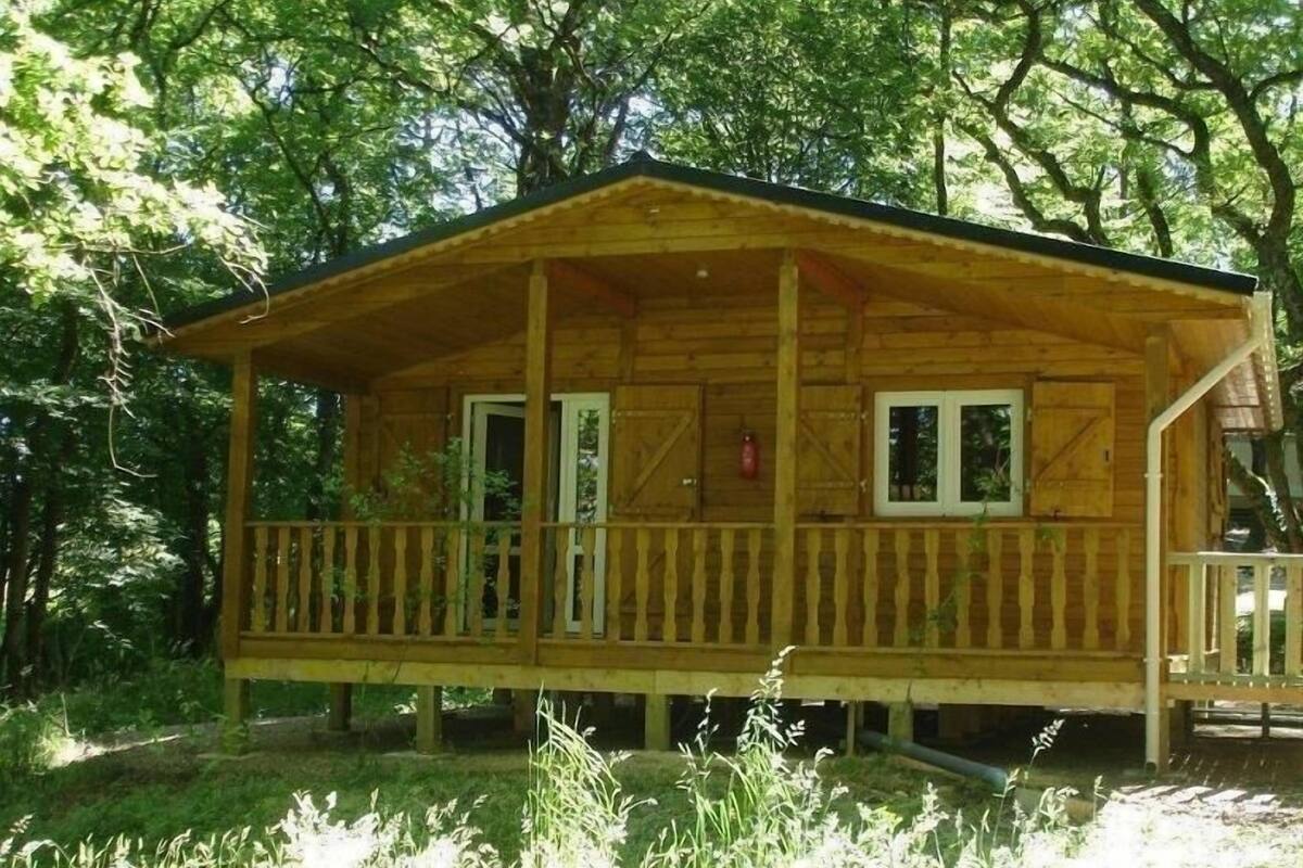 A wooden cabin with a porch, surrounded by trees.