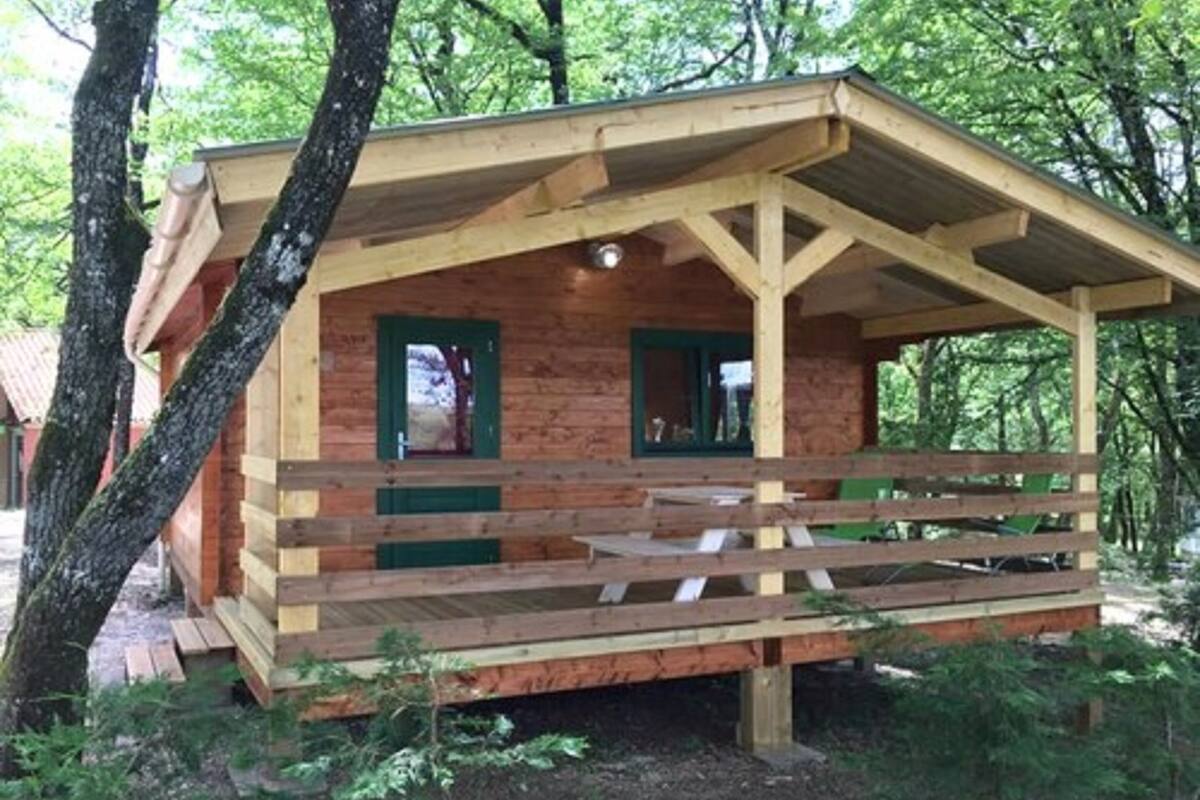 A wooden cabin with a porch, two doors, and a small window.