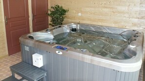 A hot tub with a control panel, a step for access, and a wooden wall in the background. - Camping la Garenne (Peyrignac)