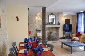 Enjoy a warm and inviting living space with a dining area for four, comfortable sofa, and a rustic fireplace.