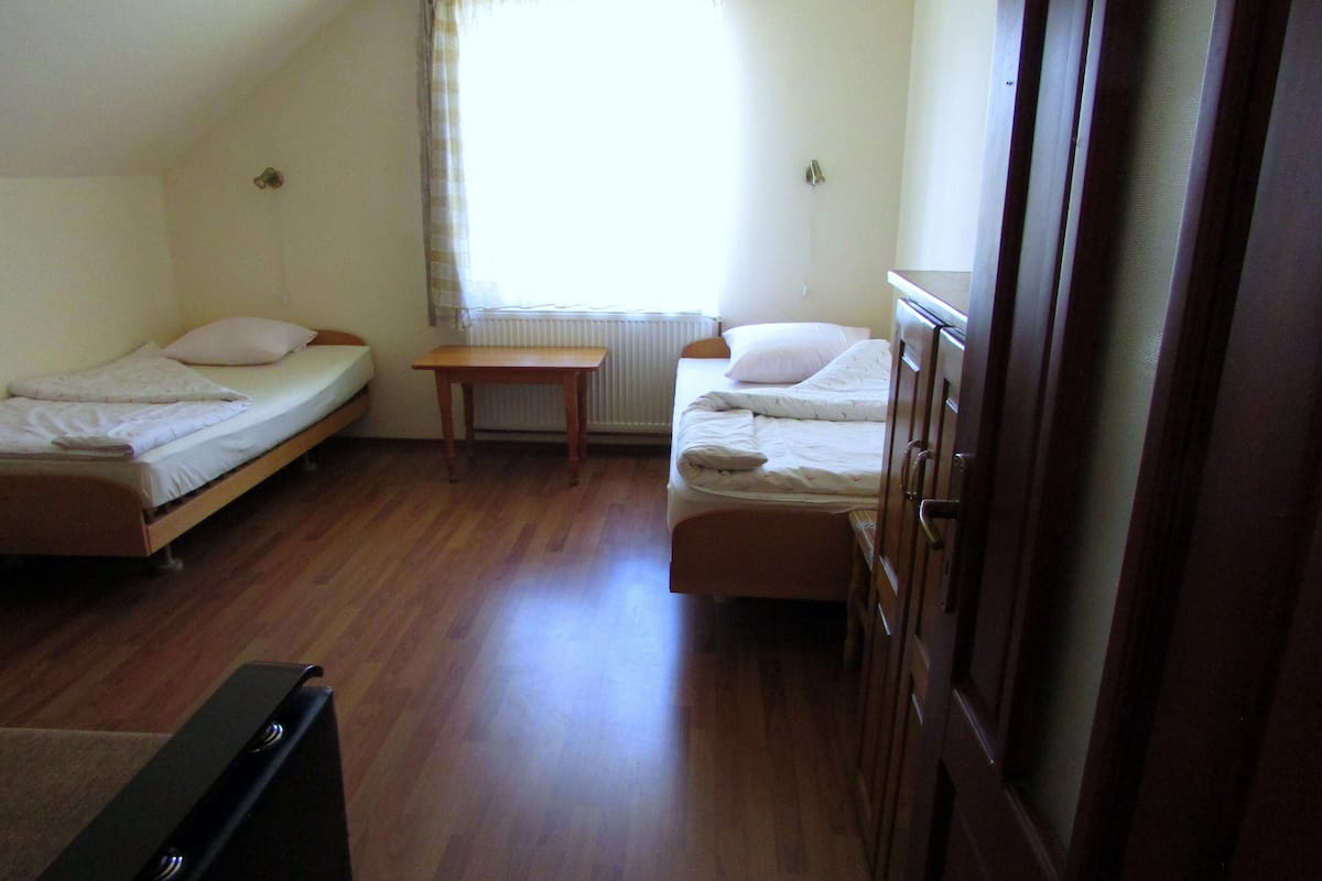 Une chambre de dortoir avec deux lits simples, une table en bois et un radiateur.