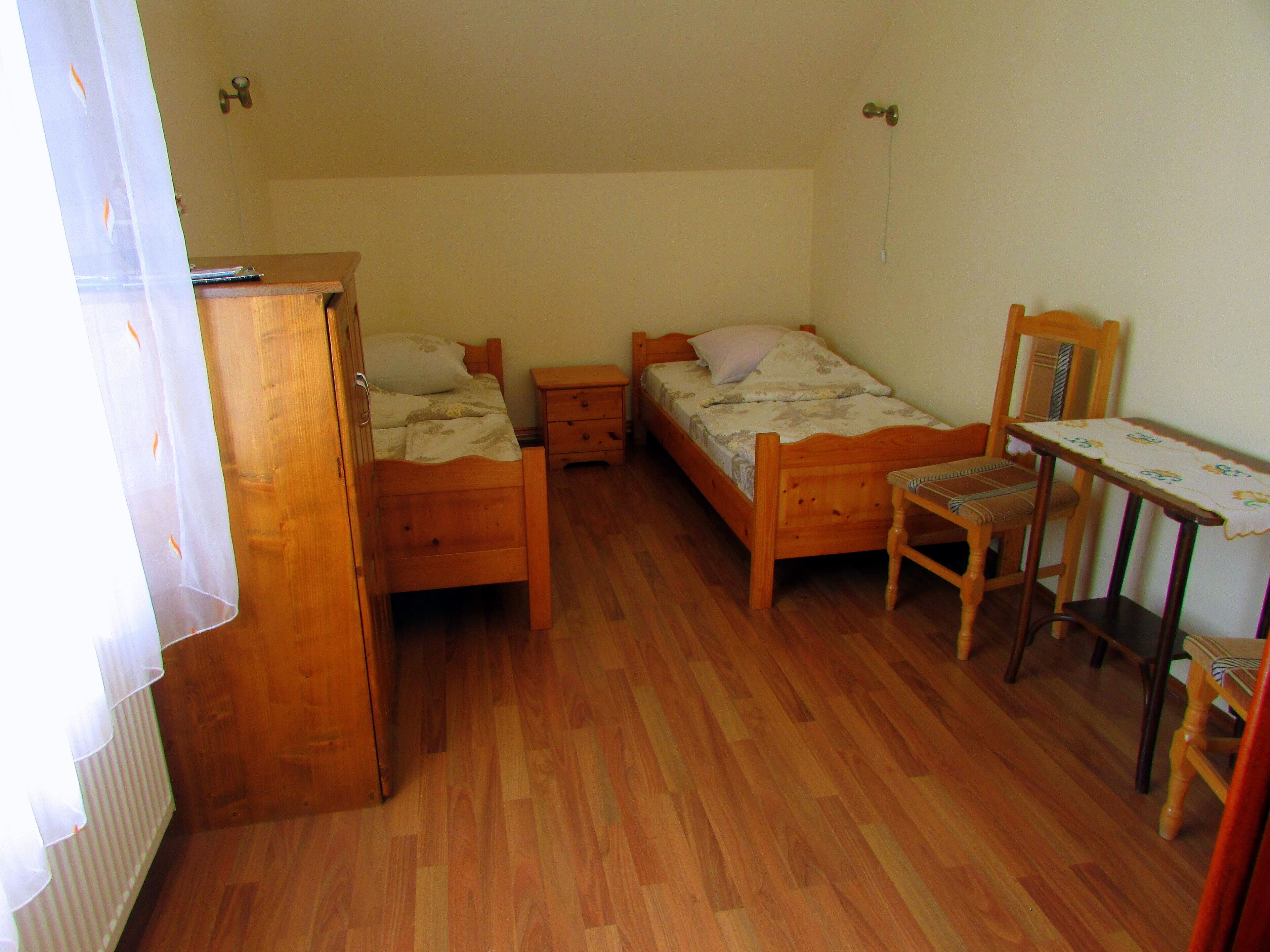 Une petite pièce en bois, avec deux lits, un bureau et une chaise.