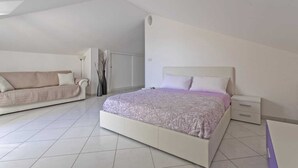 A bedroom with a bed, a sofa, and a nightstand. - Penthouse (Roseto degli Abruzzi)