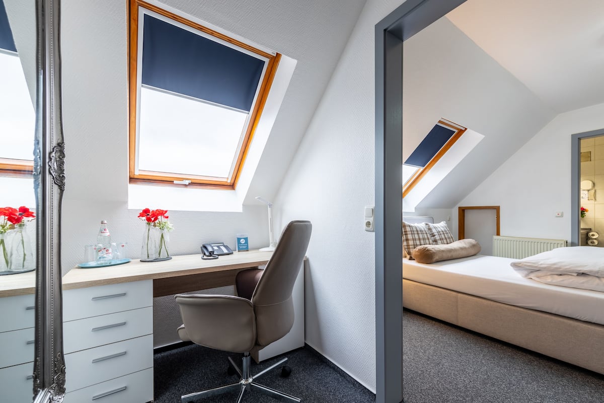 A bedroom with a skylight, a desk with a chair, and a bed.