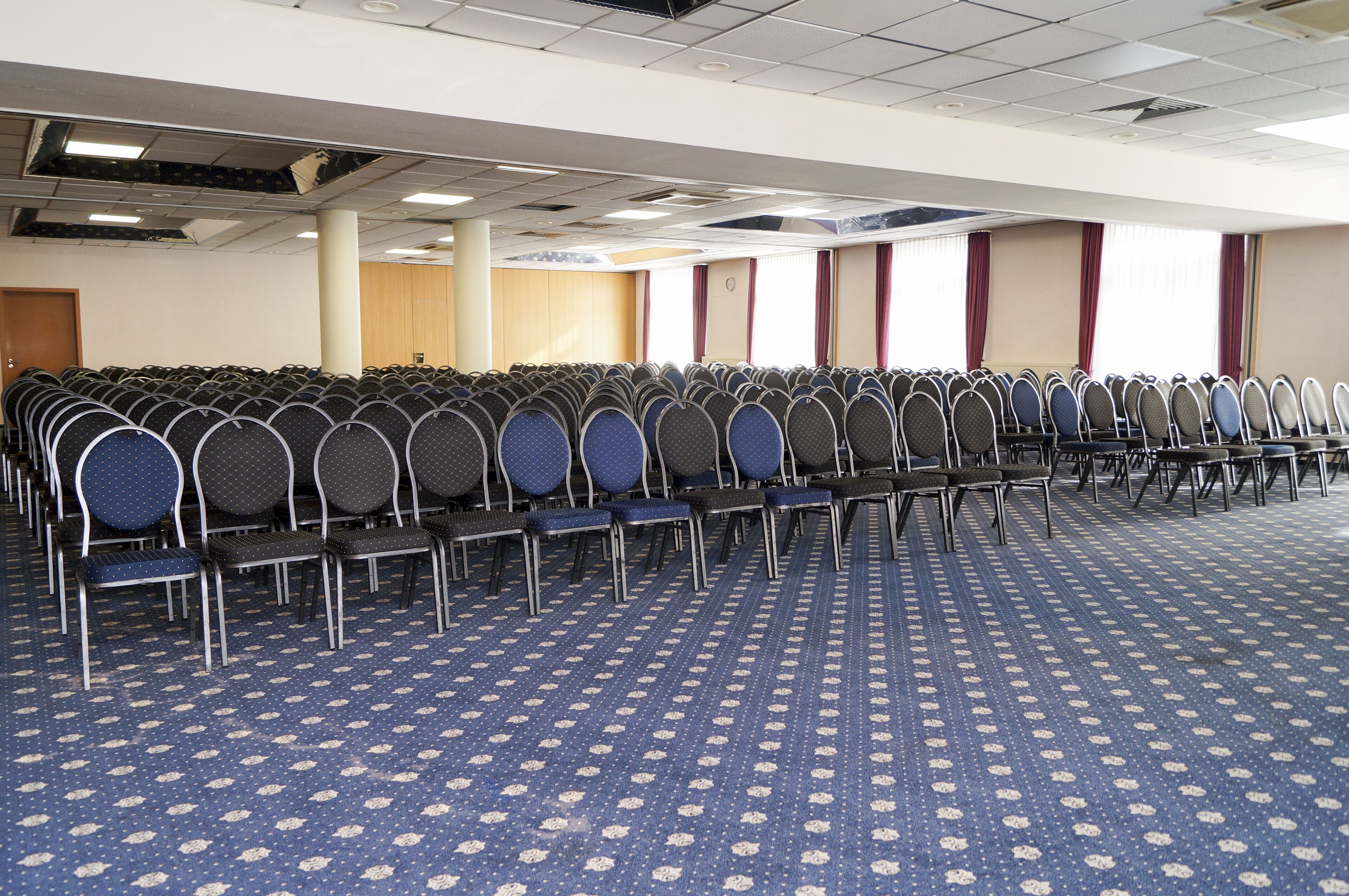 Un salón de conferencias con filas de sillas y una alfombra estampada.