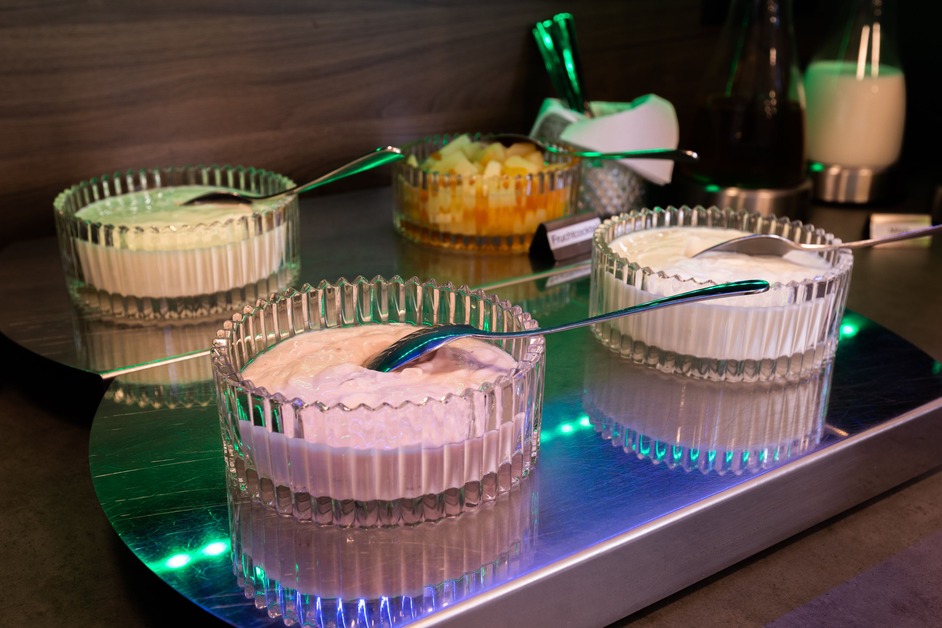 Una estación de postres con tres recipientes de vidrio transparentes que contienen diferentes opciones, cada uno con una cuchara.