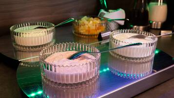 Eine Dessertstation mit drei hohen, klaren Glasbehältern, gefüllt mit verschiedenen Desserts, jeweils mit einem Löffel.