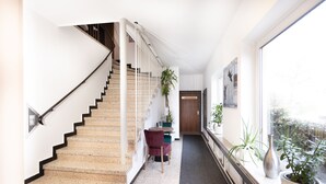 Un moderno vestíbulo de hotel con una escalera, una recepción y vistas al exterior.