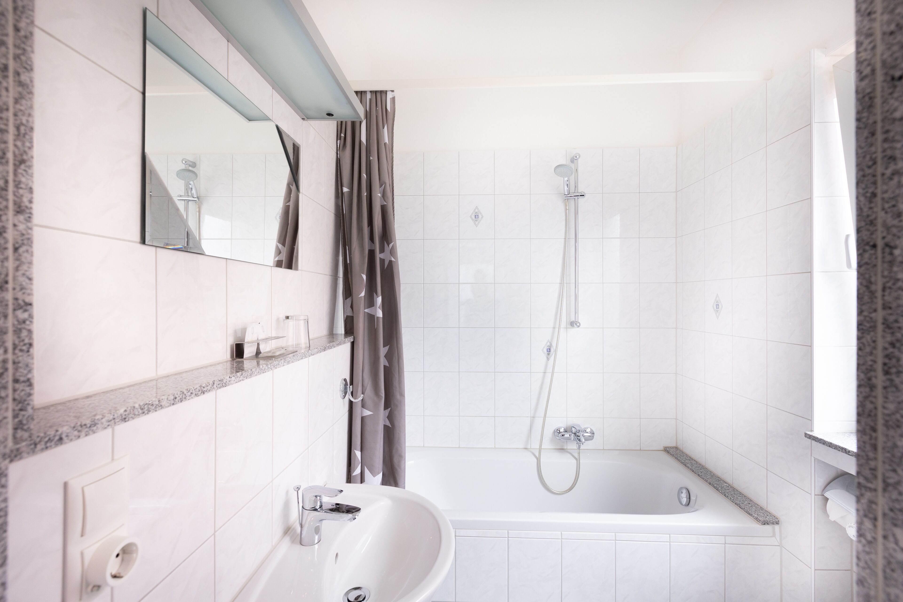 Un baño moderno con un lavabo blanco, un espejo, una ducha y una bañera.